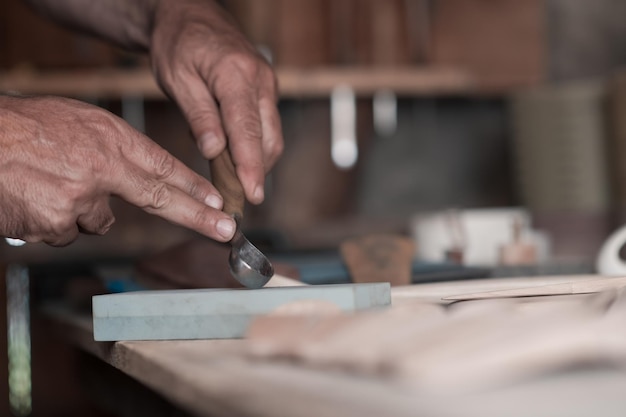 Hands carving a spoon from wood, working with chisel close up. Wooden workshop. Process of making wooden spoon. High quality photo