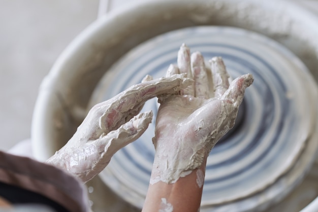 ろくろで作業した後、粘土で覆われた陶芸家の手