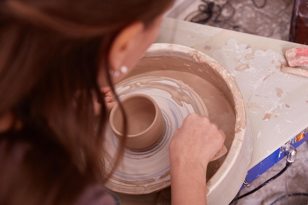 Hands of a ceramist make dishes on a potter's wheel