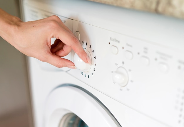 Hands changing program on washing machine