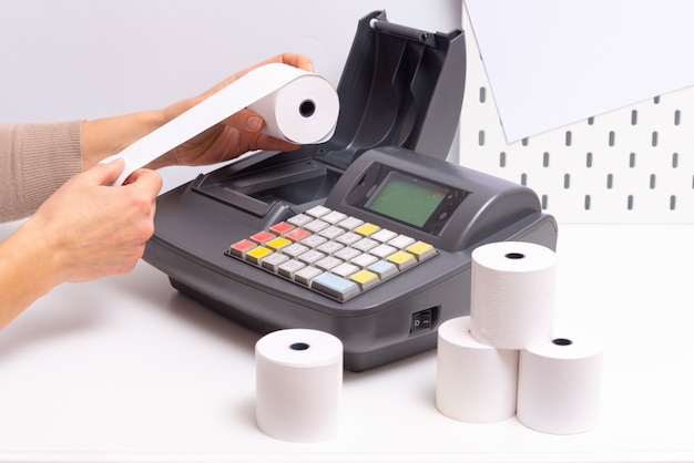 Hands changing roll in cash register