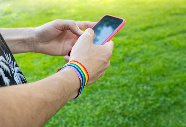 Hands chatting in a park wearing lgbt bracelet