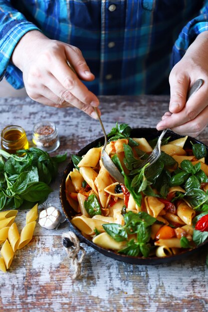 Hands of a chef cooking pasta salad