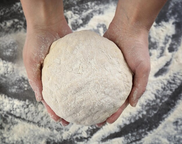 Hands of chef with dough in kitchen closeup