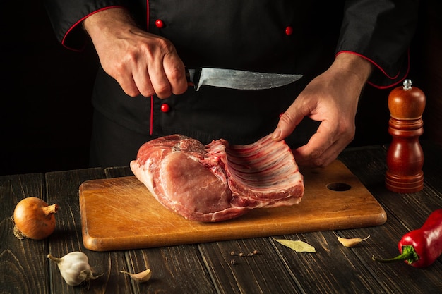 Hands of a chef with a knife in the kitchen