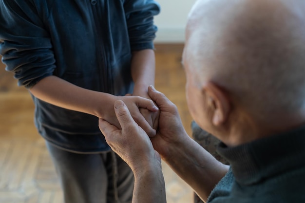 The hands of the child embracing a hand of the old man