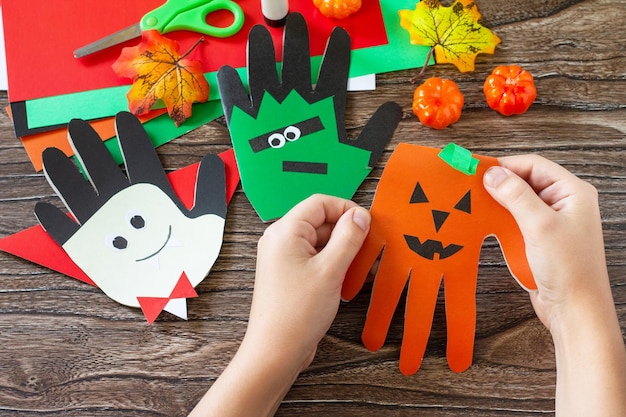 In the hands of a child Greeting card halloween on wooden table Childrens creativity project