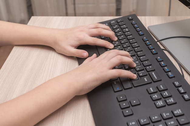 Hands of a child on home school keyboard typing