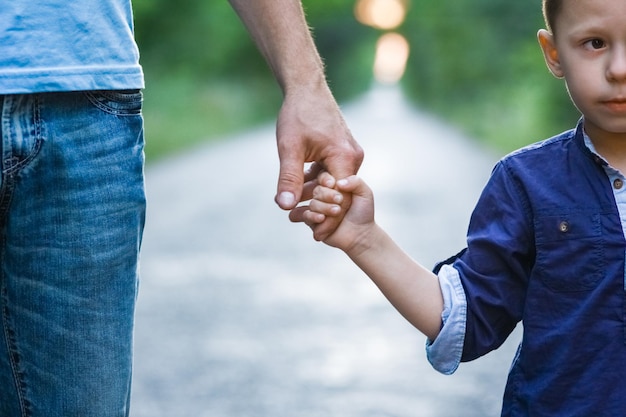 Foto mani di un bambino e di un genitore in natura sullo sfondo del viaggio su strada