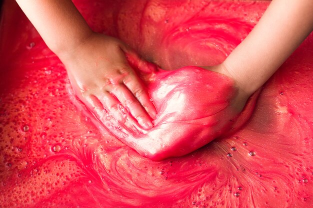 The hands of a child playing with a slime