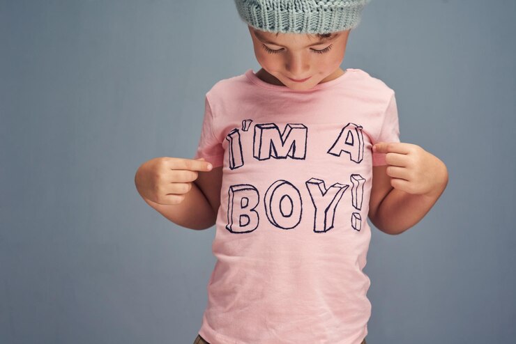 Photo hands child and point at print on shirt for gender identity style and edgy fashion model by blue background boy toddler and kid with pink clothes for choice learning and show text with promotion