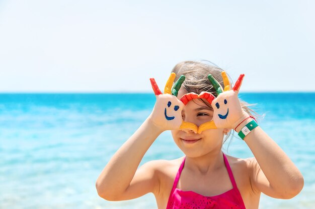 子供の手に、海に絵の具で笑顔