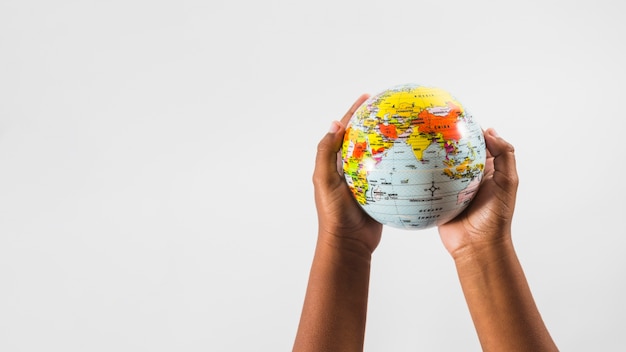 Photo hands of child with globe in studio