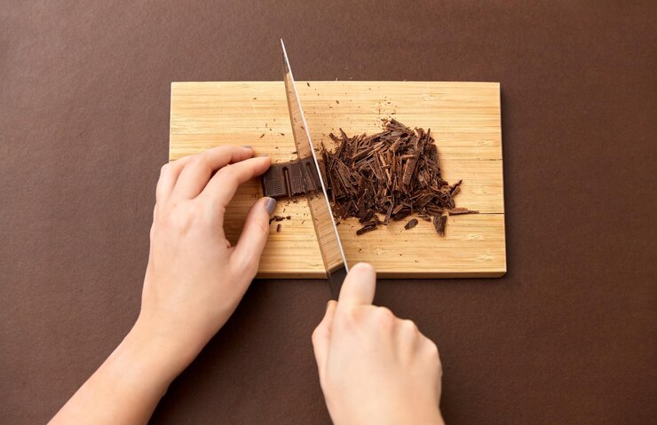 Photo 木製の板にチョコレートチップを切る手