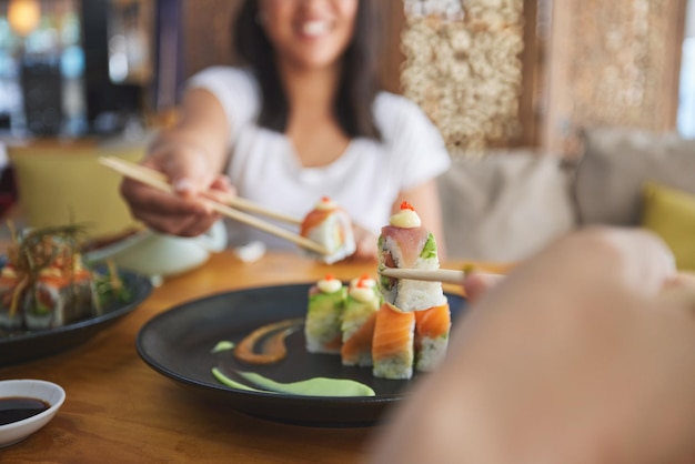 Hands chopsticks and sushi restaurant with friends smile and excited for fine dining party and share Happy women fish and healthy with culture traditional or fast food in diner bar or shop