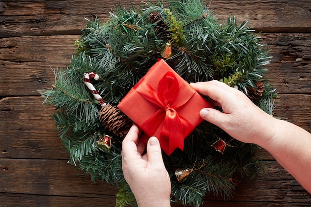 hands over Christmas wreath on wooden background