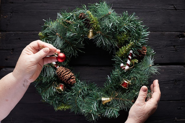 hands over Christmas wreath on wooden background