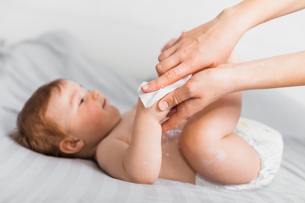 Hands cleaning baby with baby wipe