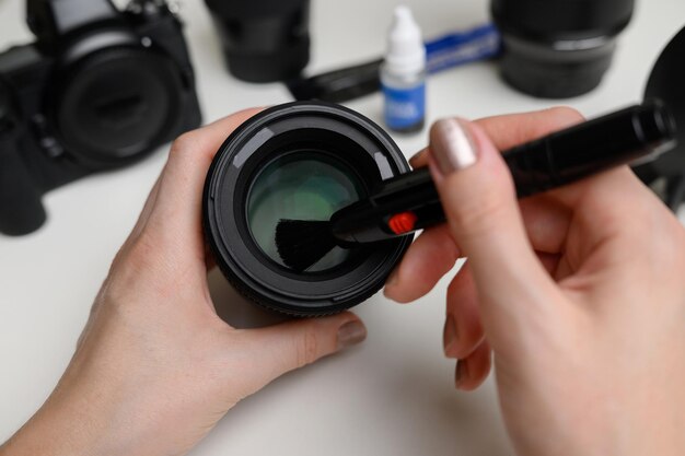 Фото Руки очищают объектив цифровой камеры от пыли специальной щеткой для чистки.