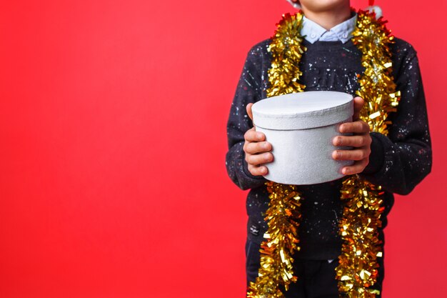 Hands close-up, holding gift box on red wall