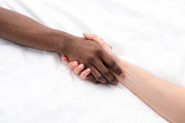 Hands close up multiracial couple african man and caucasian woman romantically touch each other handshake on white lovers making Passion love