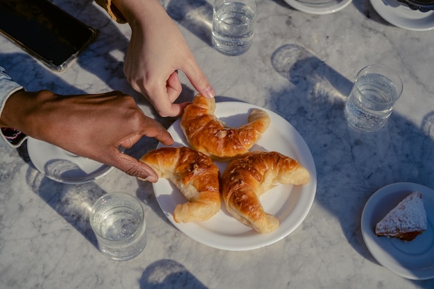 Photo hands clutching argentine croissants on a marble table in an outdoor cafeteria