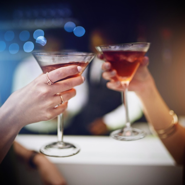 Hands cocktail and party with friends drinking together in a nightclub for a new year celebration Glass toast and event with a female and friend celebrating with a cheers in a music club or disco