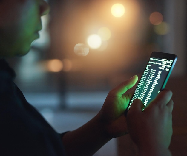 hands code and hacker with phone for cyber attack fraud or data breach with bokeh at night mobile criminal or person hacking on screen for network security or programming dark web malware closeup