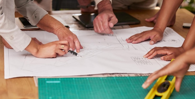 Сотрудничество рук и архитектура с командой дизайнеров, планирующей на столе с использованием плана Планирование здания и совместная работа с группой инженеров, работающих над разработкой проекта