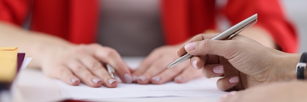 Hands of colleagues with ballpoint pen lying on documents closeup