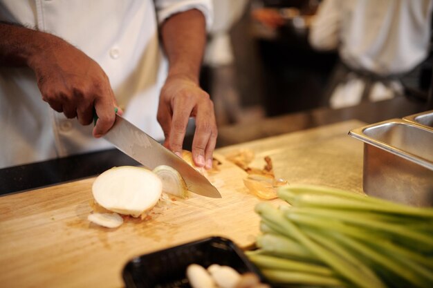 Hands of cook slicing onions for main dish