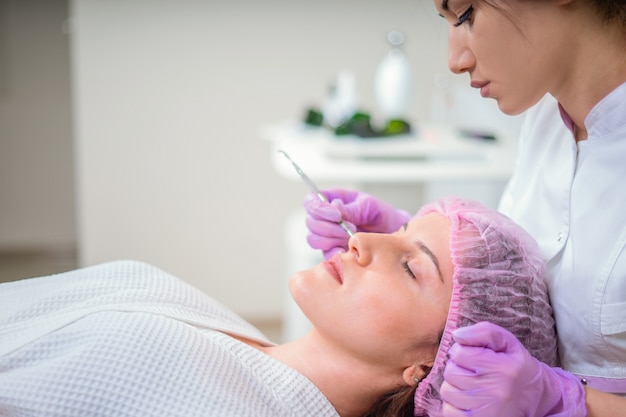 Hands of cosmetologist making facial cleaning with special instrument