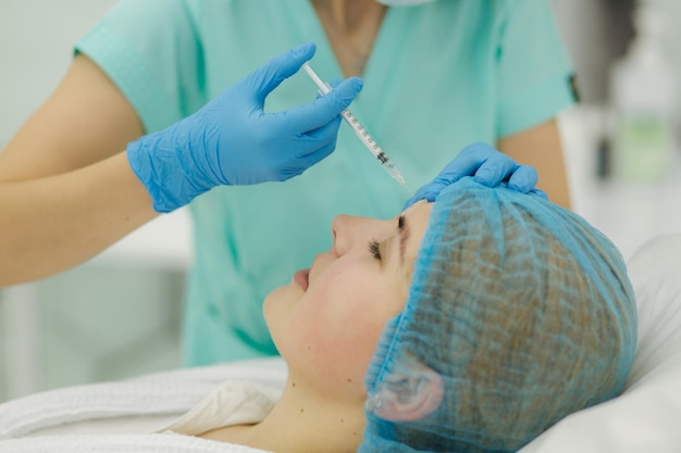 Hands of cosmetologist making injection in face lips Young woman gets beauty facial injections in