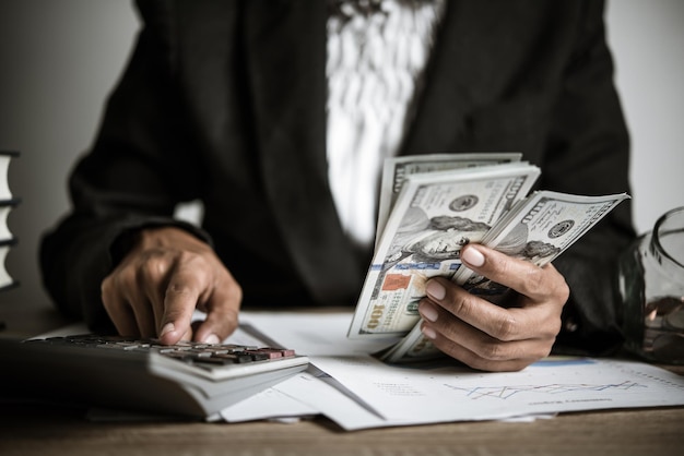 hands counting dollar banknotes on wooden table
