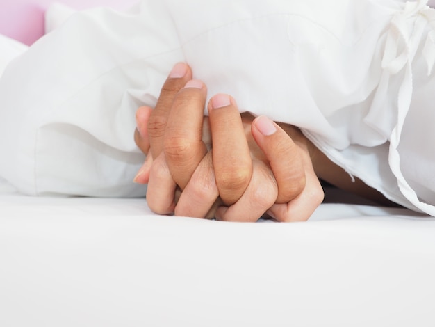 Hands of couple lovers having sex on a bed in morning with lust and love