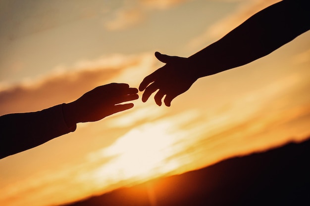 Foto le mani di una coppia al tramonto silhouette del concetto di mano che aiuta