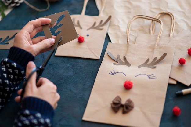 Hands crafting adorable reindeer decorated christmas paper bag