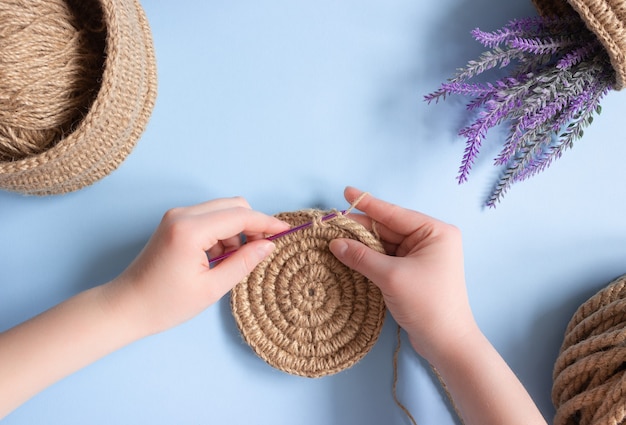 Hands crochet a round napkin made of jute