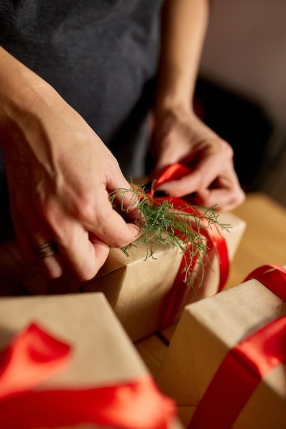 Hands of cropped unrecognisable woman packing Christmas present
