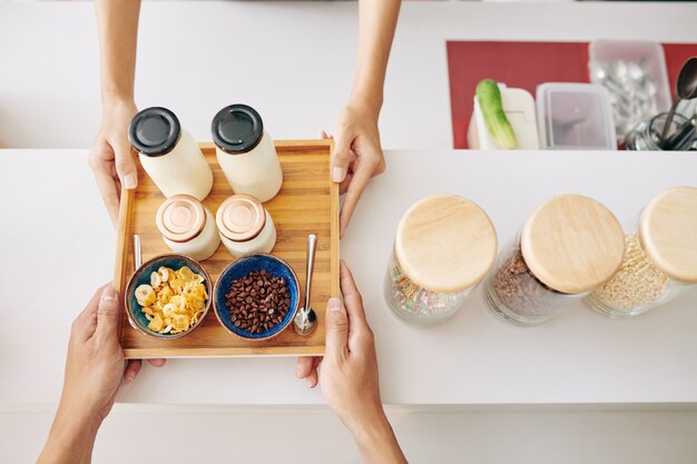 Hands of customer buying breakfast consisting of fresh yogurt, cornflakes and chocolate chips