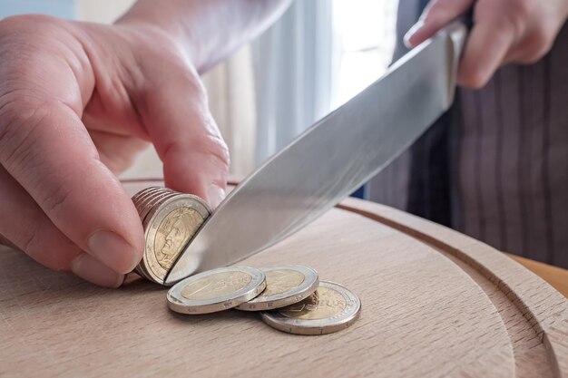 Hands cut euro coins with a knife separating them like pieces of food on a cutting board