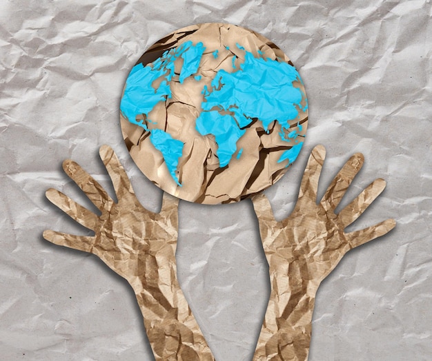 구겨진 종이에서 잘라낸 손은 지구본 모양으로 올라갑니다. 환경 보존 생태학의 개념