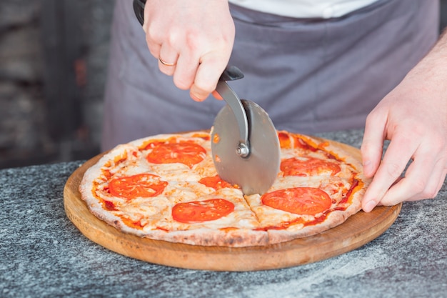 Hands cutting a delicious pizza