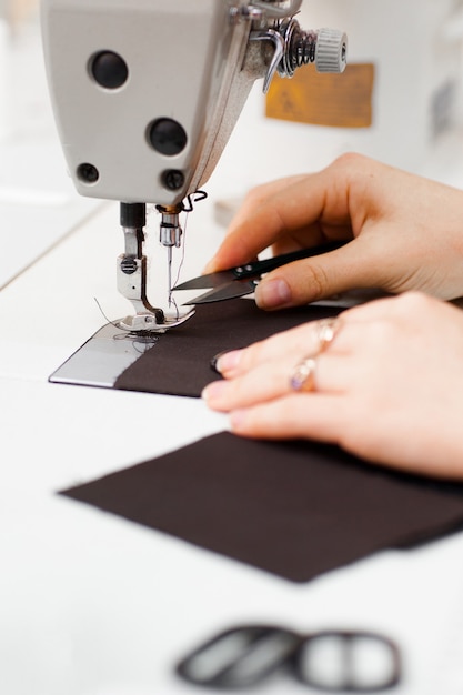 Hands cutting thread on sewing machine