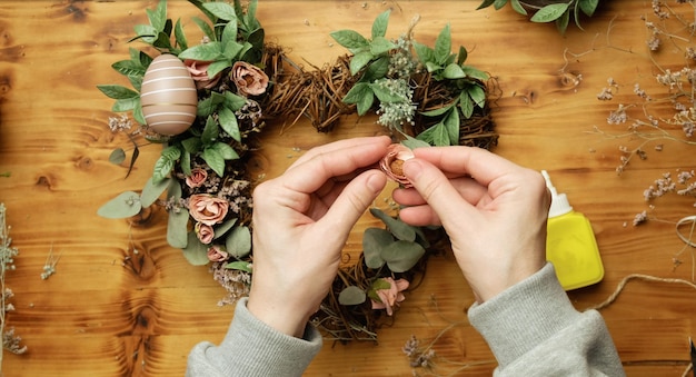 家の装飾のためのイースターの花の花輪を飾る手