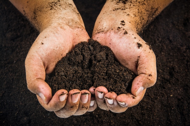 Hands dirty with clay , soil background 