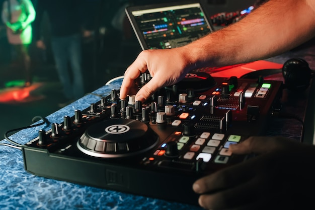 Mani di un dj in una cabina che gioca sul mixer