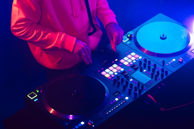 Hands of a dj creating and regulating music on dj console mixer at club concert