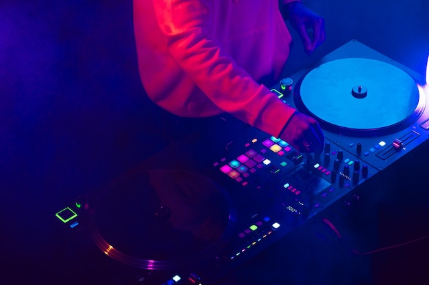Hands of a dj creating and regulating music on dj console mixer at club concert