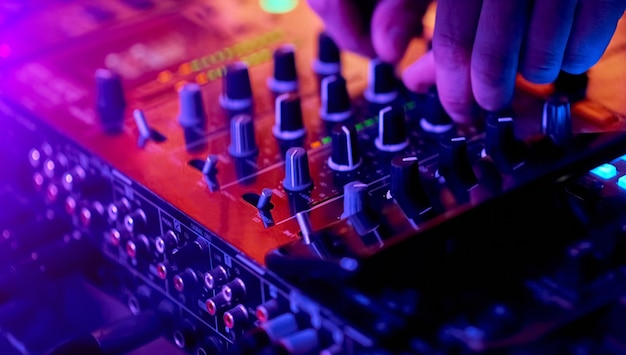 Hands of dj mixing tracks on professional sound\
mixer..closeup,knobs and regulators in focus. high quality\
photo